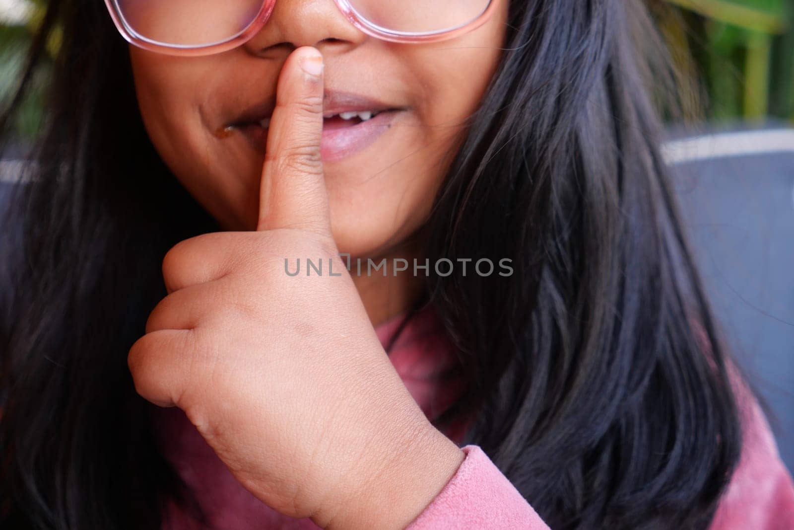 kid raising her hand indicating to stop talking or to be silent .