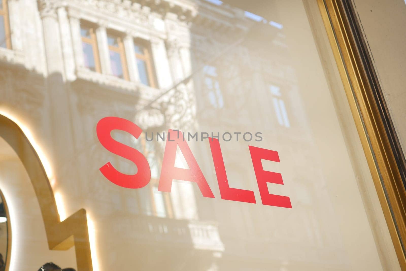 Large red Sale text letters on a glass wall obstruct a view inside the popular fashion store. High quality photo