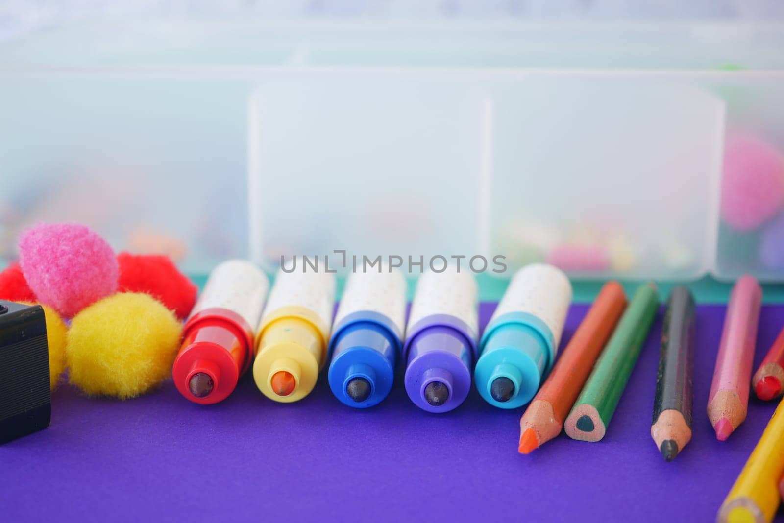 Vibrant markers, colorful pencils, and fluffy pompoms are arranged to inspire creativity