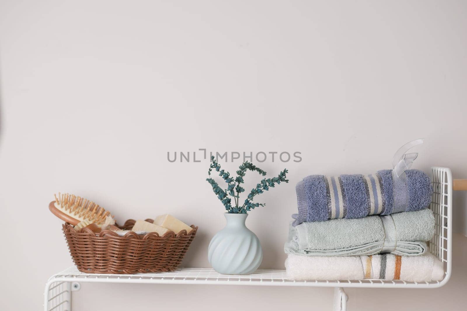 A chic bathroom shelf with neatly arranged towels, a vase, and elegant natural decor accents