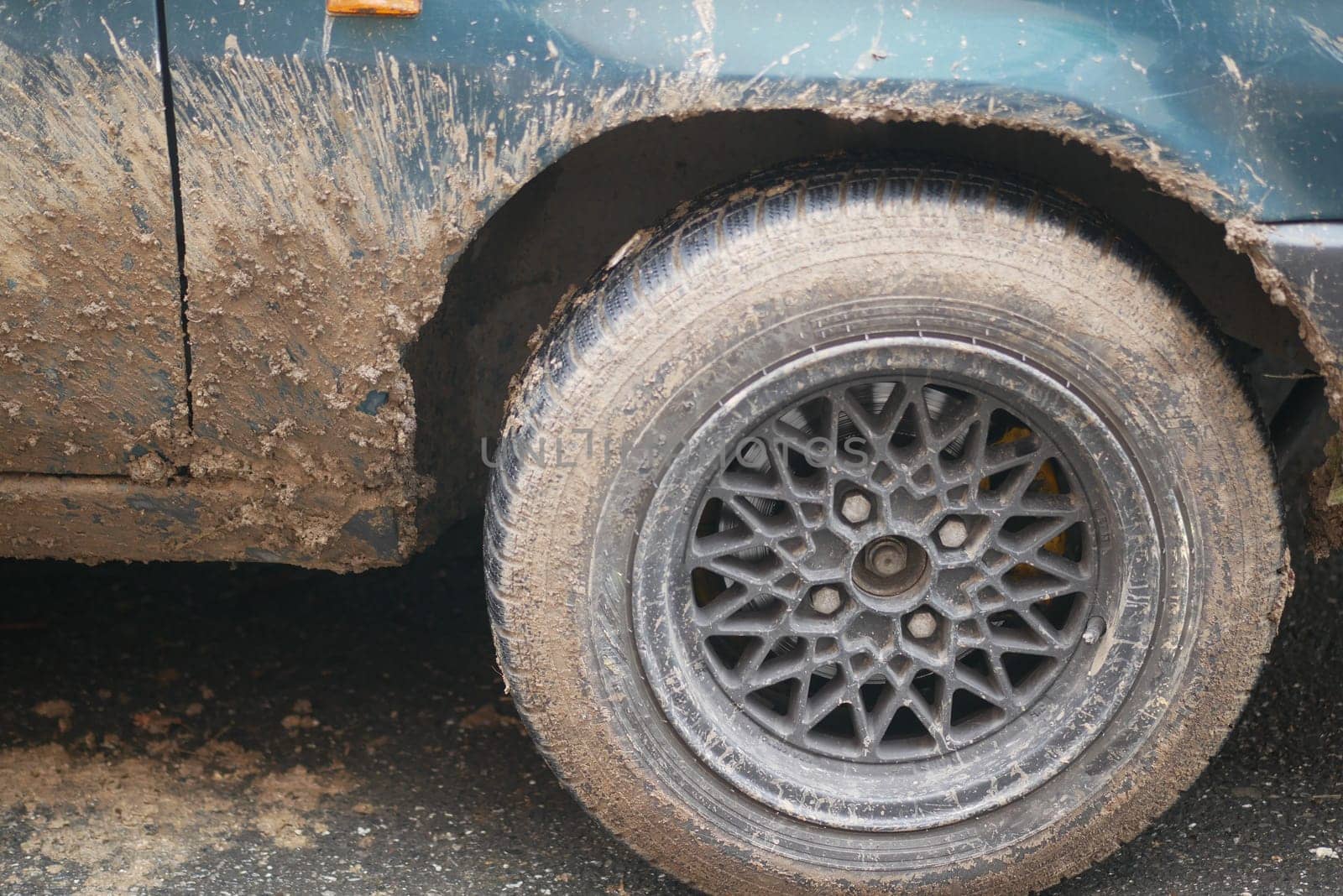 Closeup of a muddy, weathered wheel on an old classic car, highlighting its rugged design