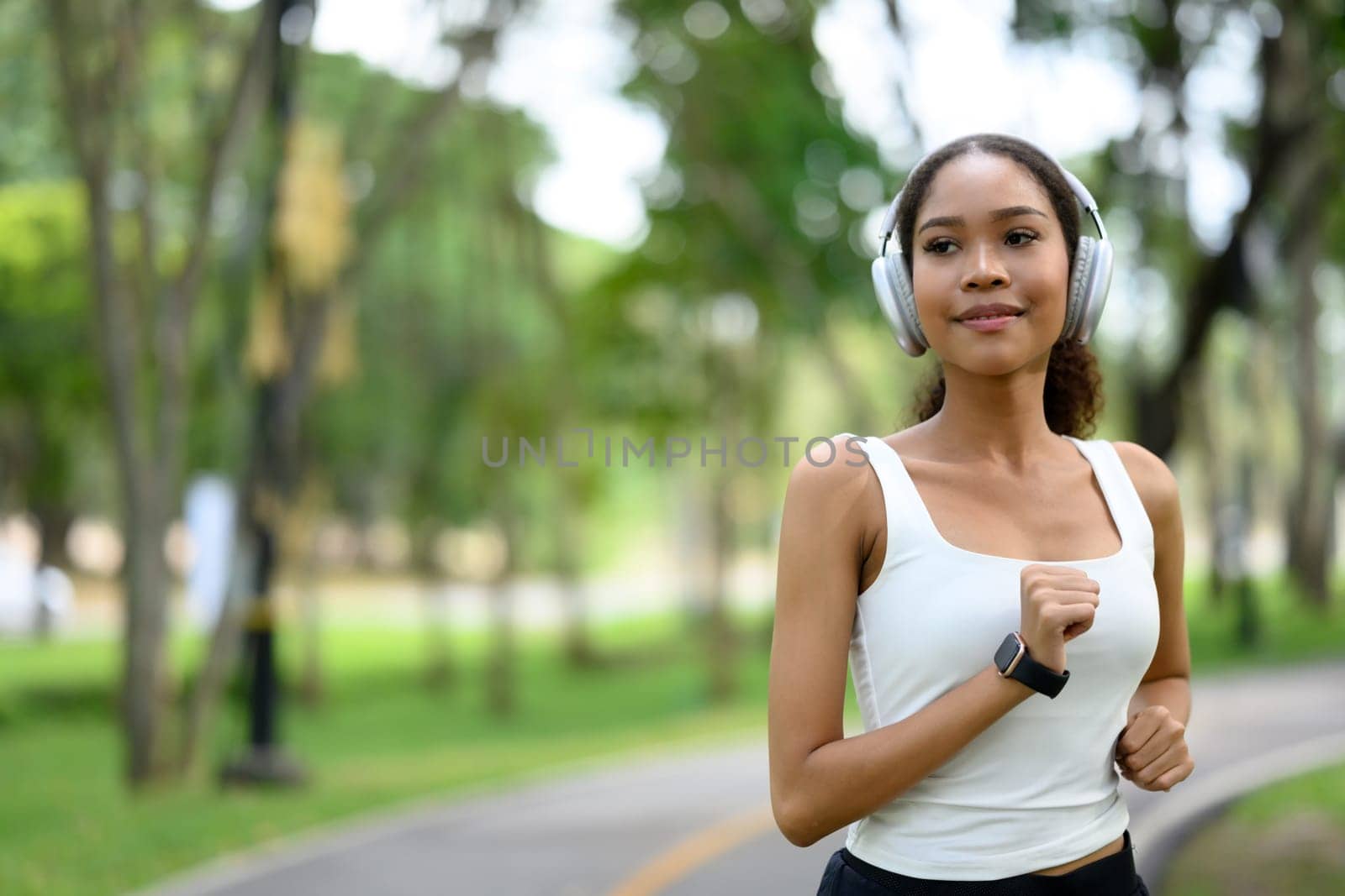 Young sporty woman on a morning jogging in the park, listening to music with headphones.