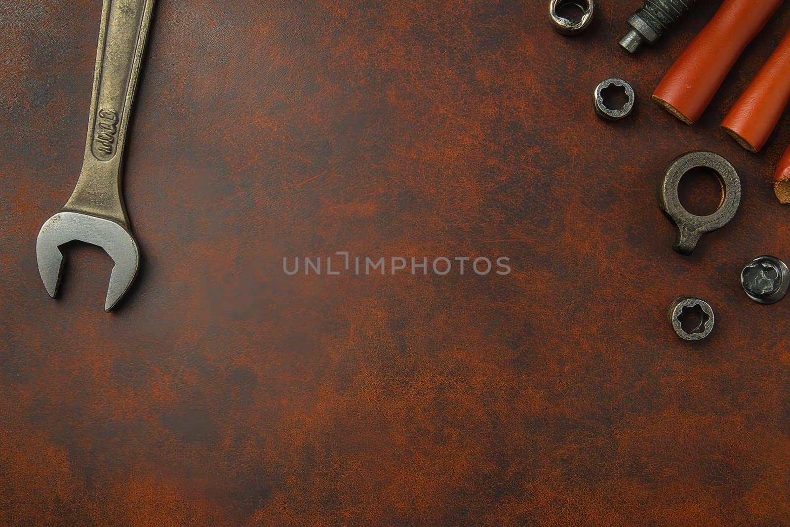 A collection of vintage tools including a wrench and various nuts on a rich brown leather background, perfect for workshop themes and DIY projects.