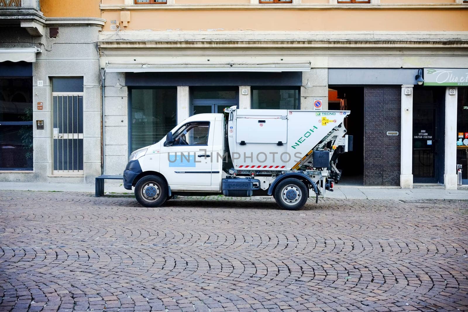 Cremona, Itally - October 6th 2024 Eco-friendly waste management highlighted by a white df zhidou d2 electric garbage truck parked on a cobblestone street in an urban setting