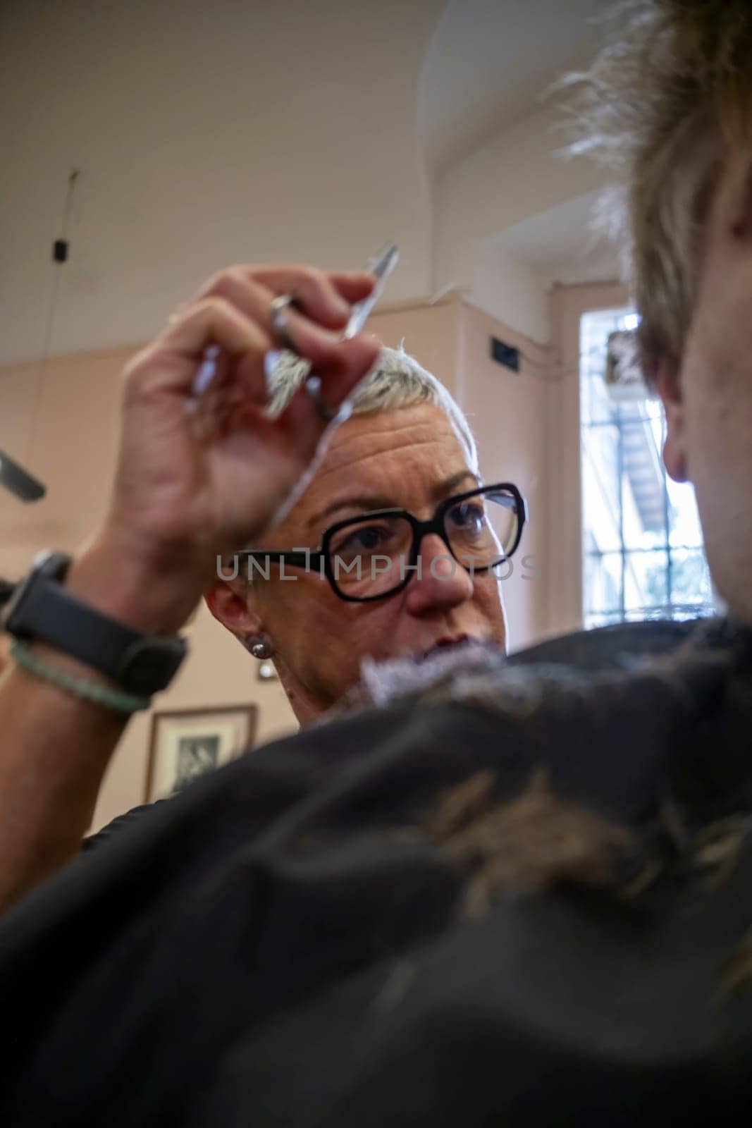 Cremona, Italy - November 27th 2024 Hairdresser cutting hair of customer in barbershop in cremona, italy