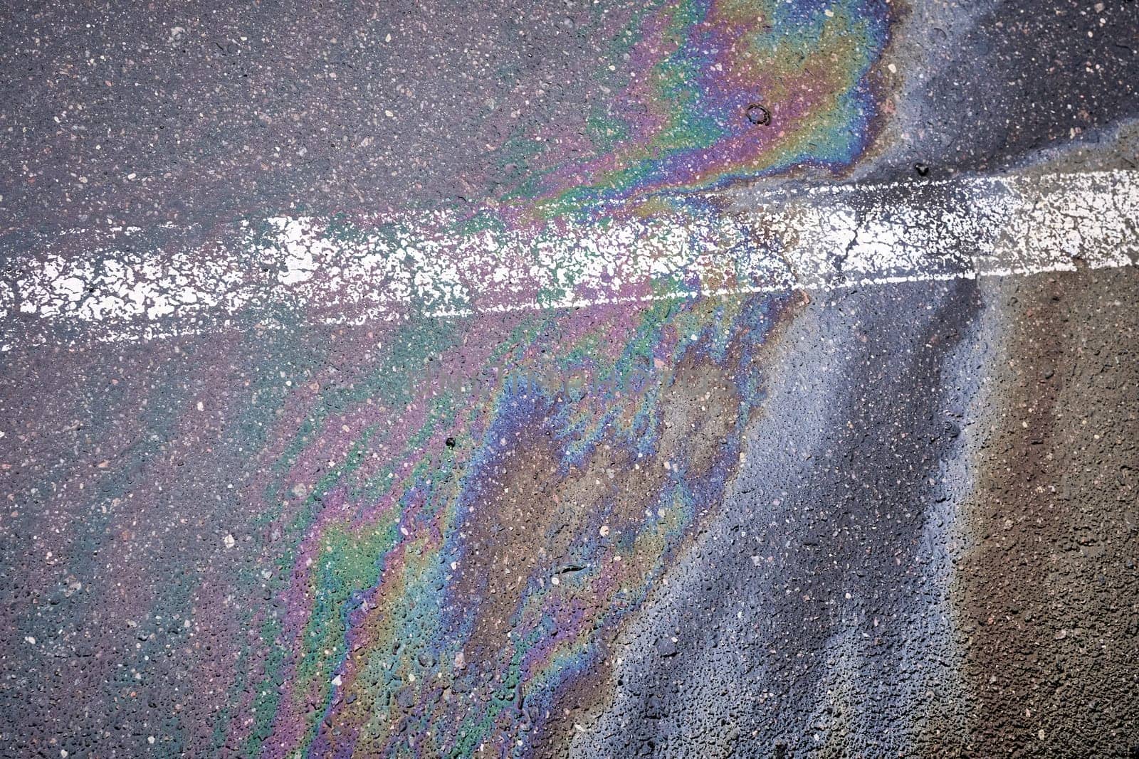 Oil spill on wet asphalt, parking lot with dividing line.