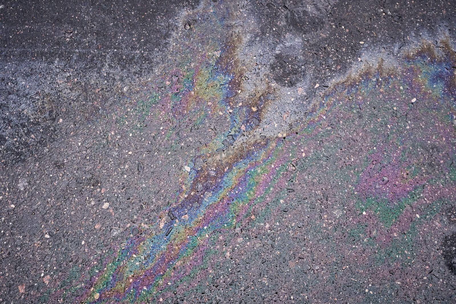 Rainbow stain from gasoline or oil leak on asphalt road