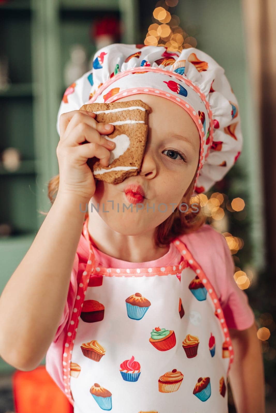 .a girl child in the kitchen with a Christmas tree is preparing or cooking ginger cookies for Christmas or New year