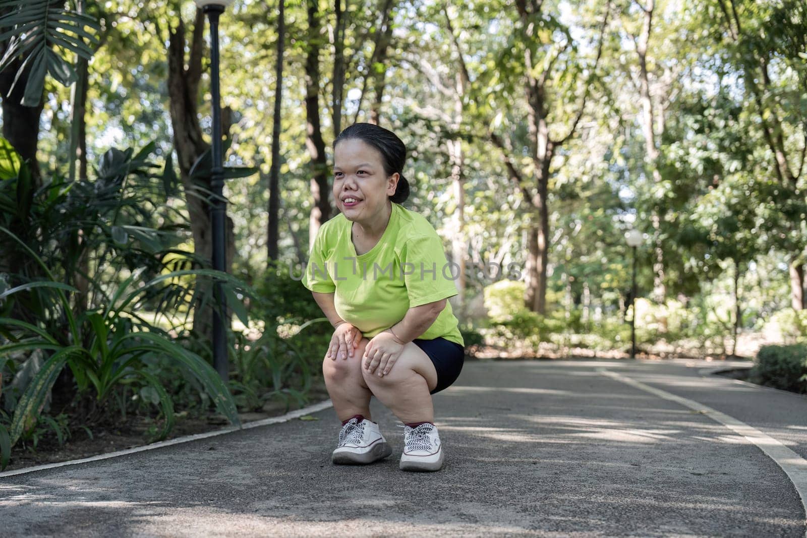 A person with a small body actively stretching and exercising in a vibrant park, showcasing strength and determination.