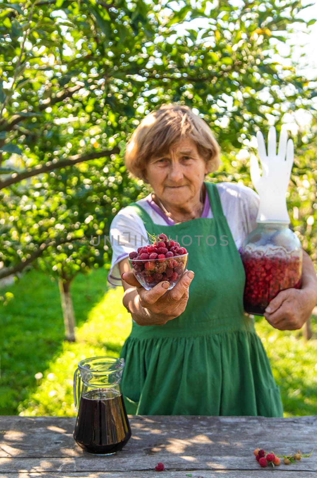 Grandma makes wine from raspberries in the garden. Selective focus. drink.