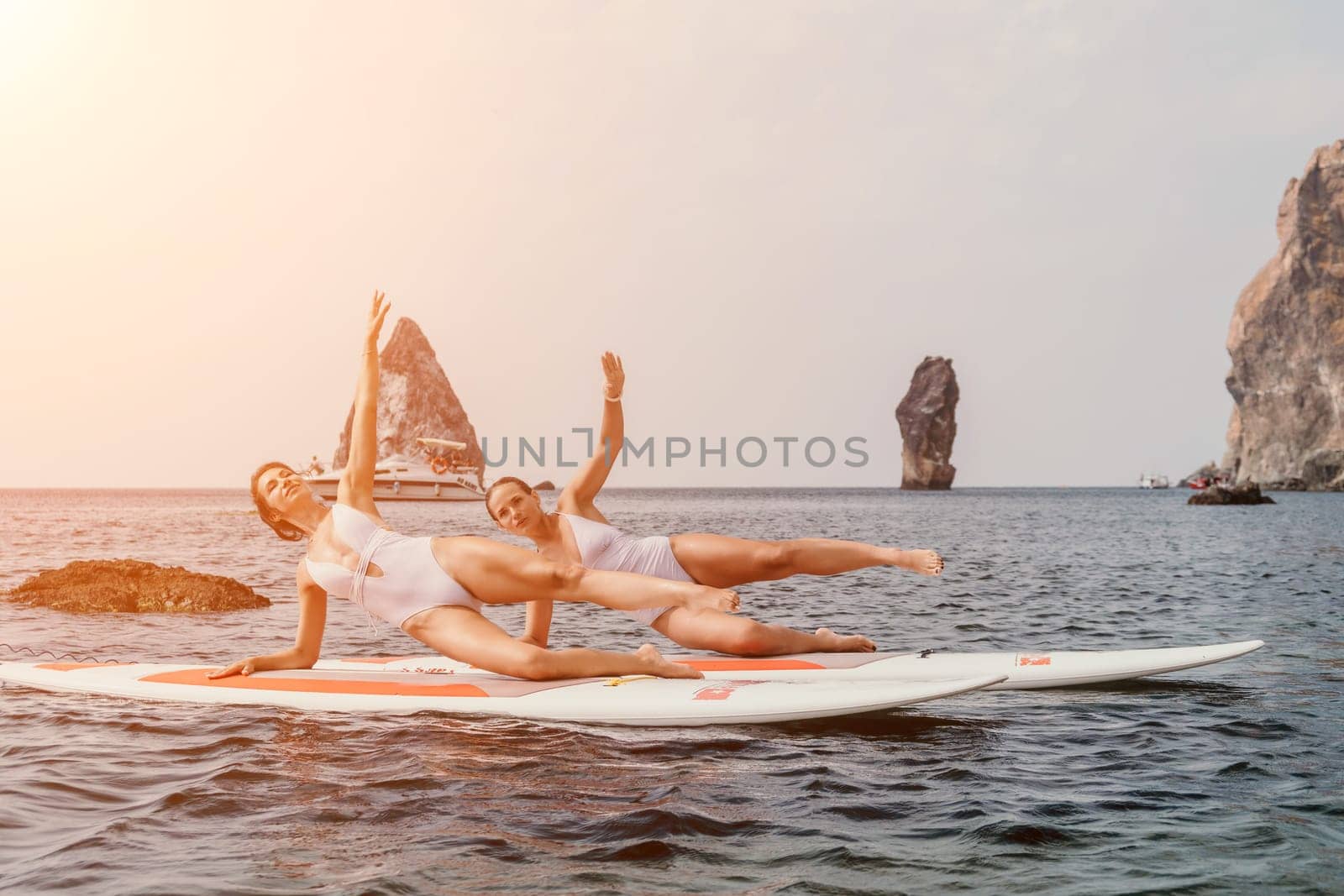 Woman sup yoga. Happy sporty woman practising yoga pilates on paddle sup surfboard. Female stretching doing workout on sea water. Modern individual female hipster outdoor summer sport activity. by panophotograph