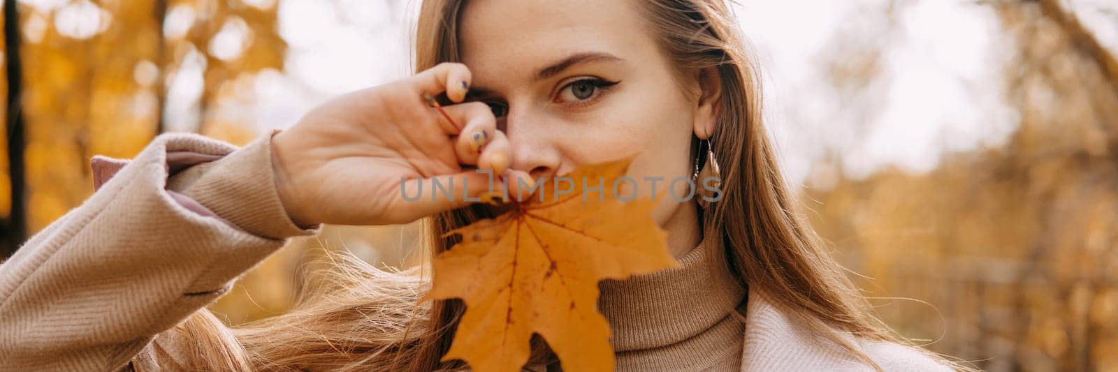 Portrait of a woman with an autumn maple leaf. Railway, autumn leaves, a young long-haired woman in a light coat coat, close-up by Annu1tochka