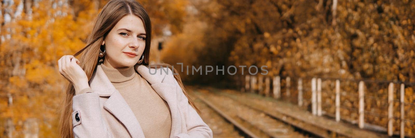 beautiful long-haired woman walks through the autumn streets. Railway, autumn, woman in a coat. by Annu1tochka