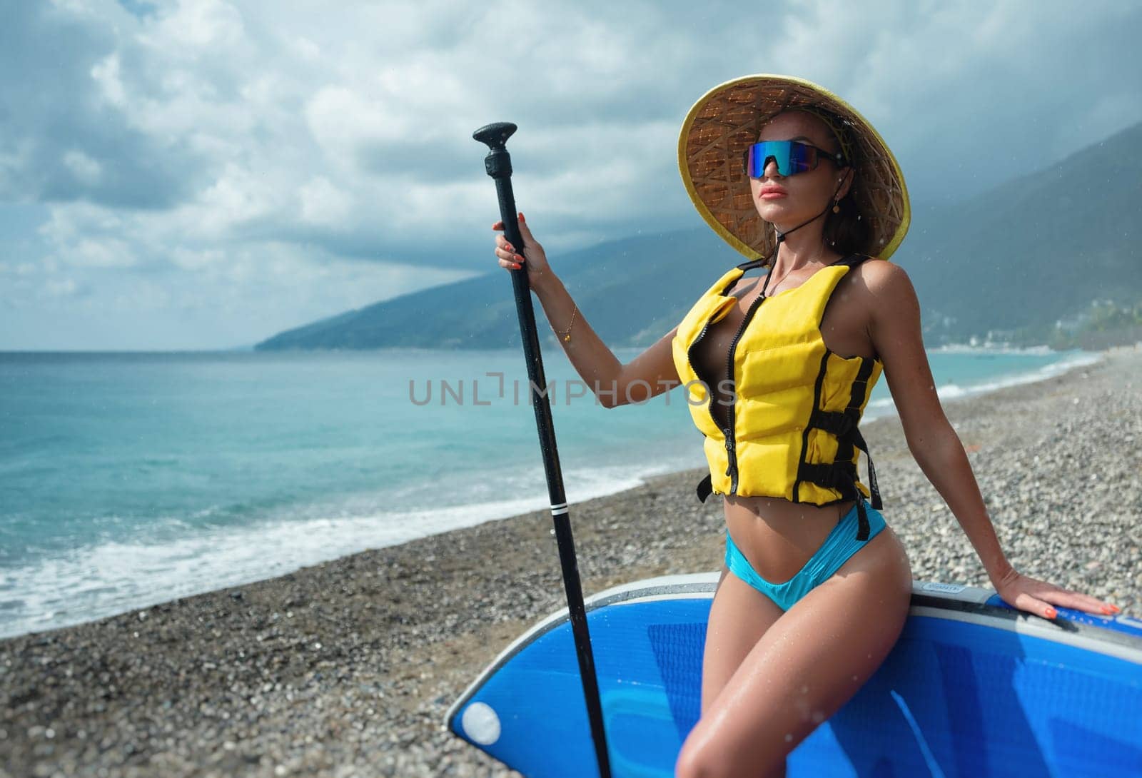 the sexy girl in life jacket with sup board at sea