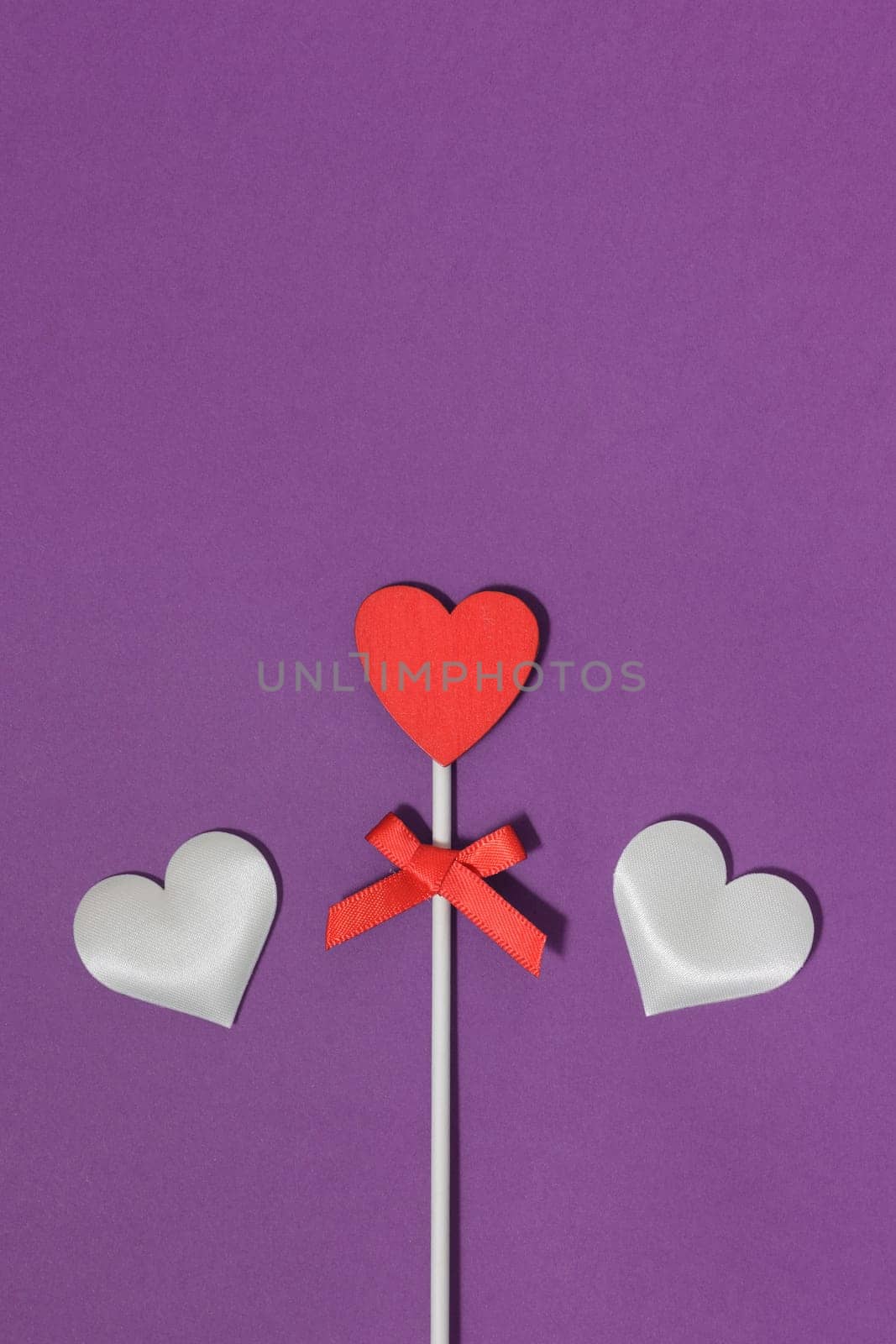 Three hearts on a purple background. Heart stacked in a stick like a lollipop, on a purple background