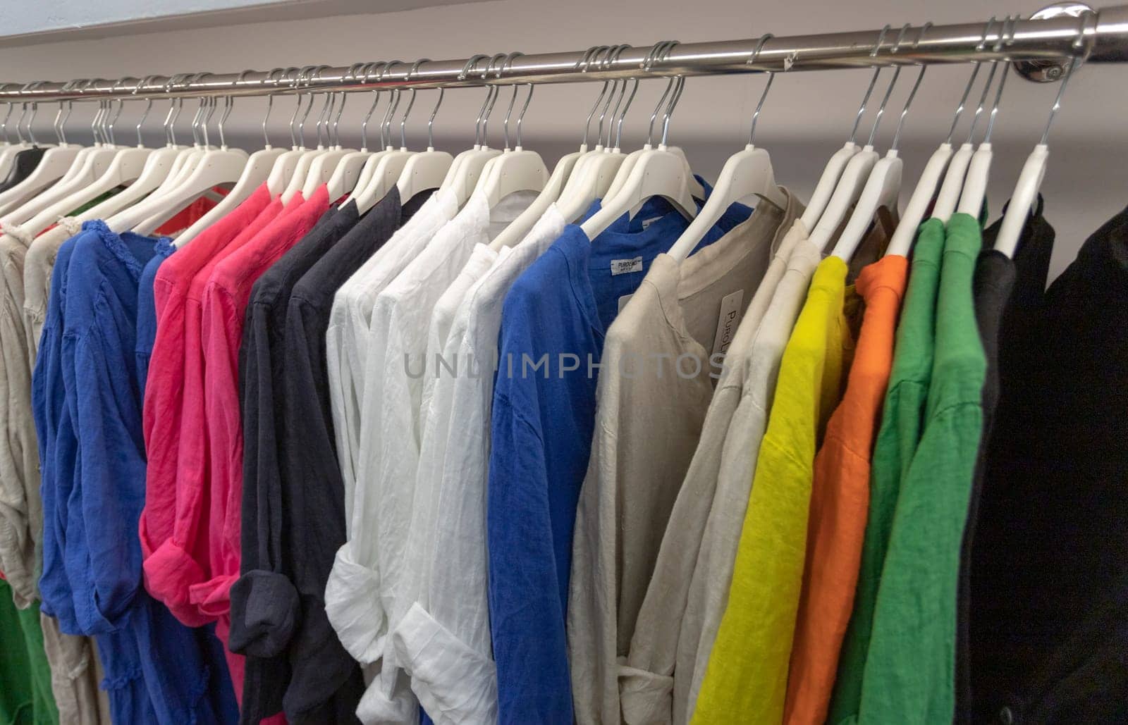 Corfu, Greece-September 15, 2023: Women's clothing store. Cotton dress shirts, summer dresses hanging on hangers. Collection of fashionable women's clothes in a retail store.