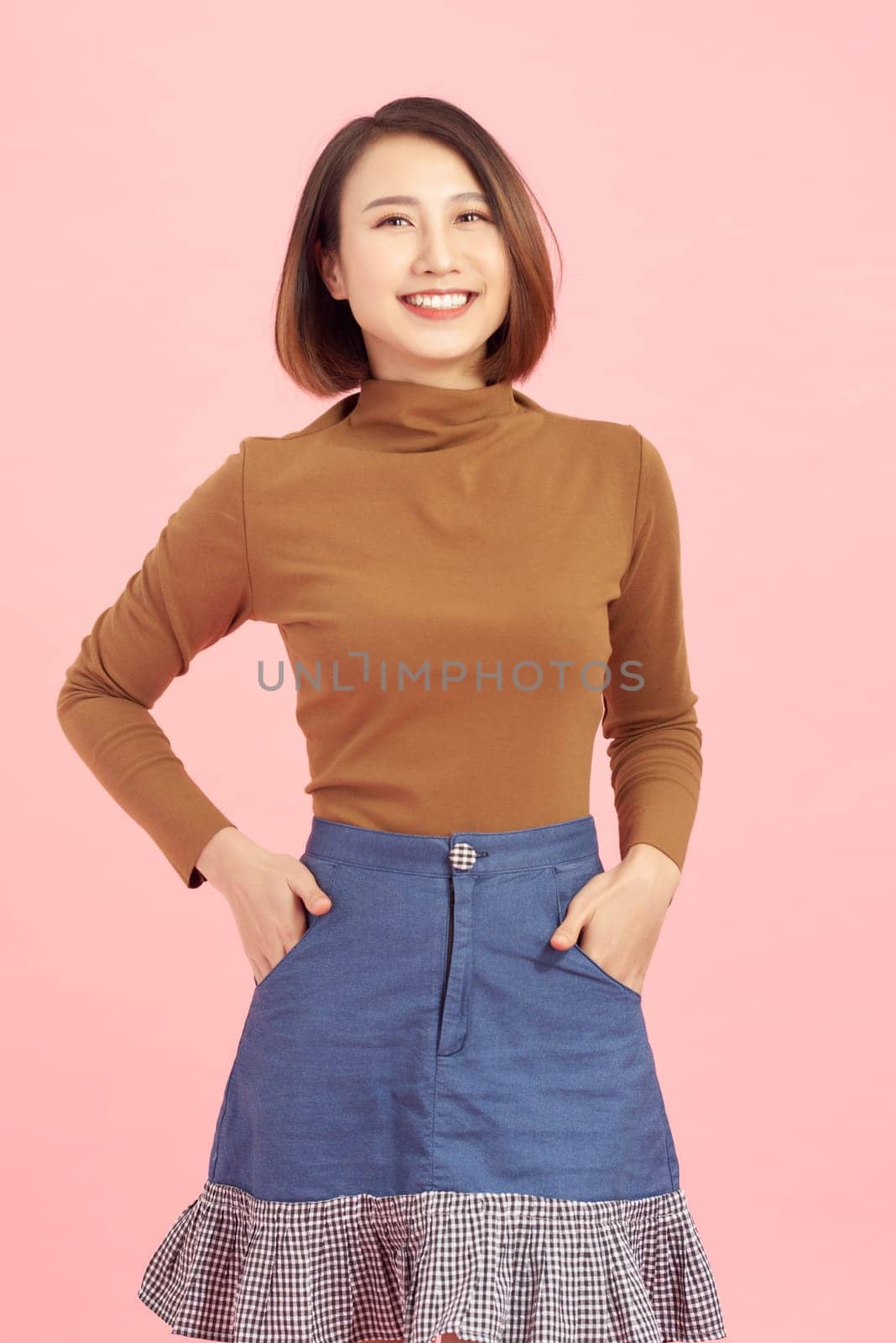 Attractive young Asian woman smiling isolated over pink background.