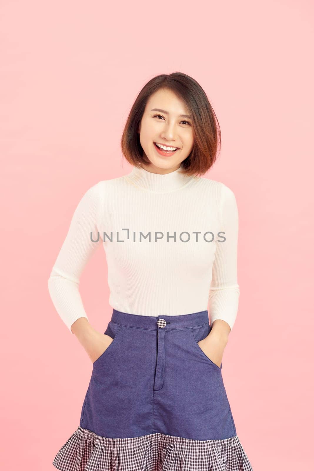 portrait of smiling Asian woman standing isolated on pink background.