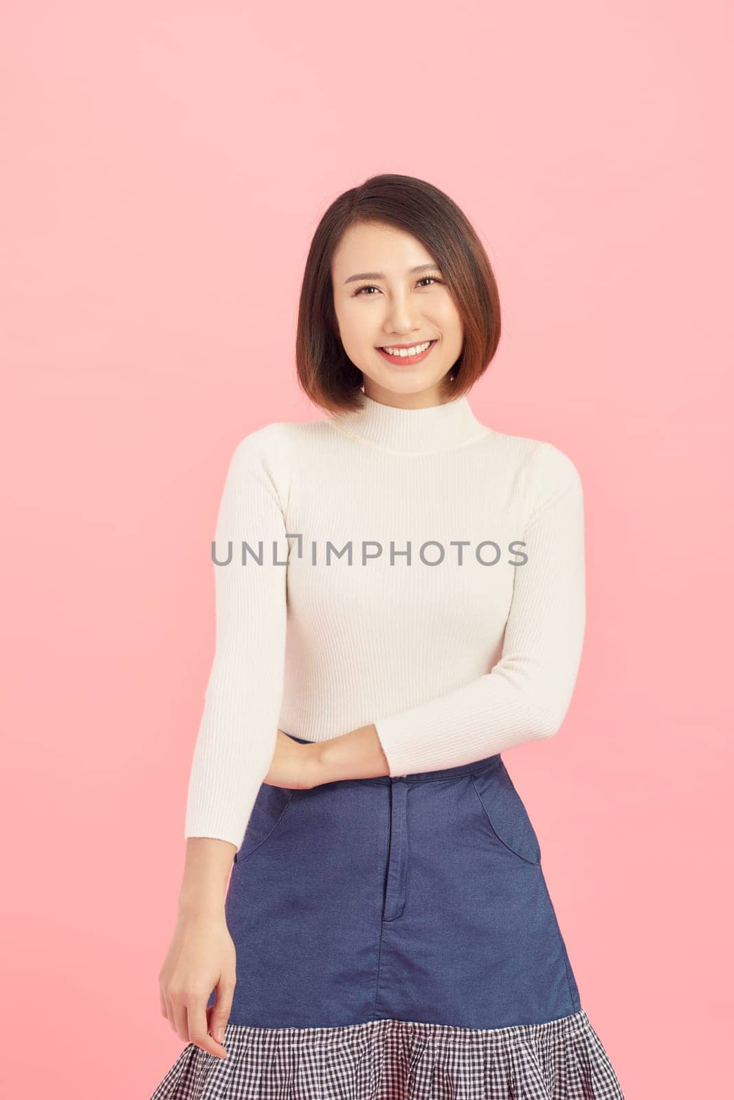Portrait of smiling Asian woman standing isolated on pink background.