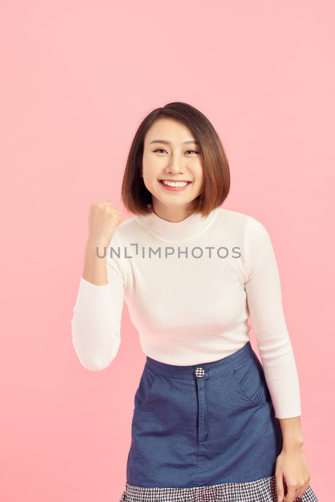Asian businesswoman scream with joy and happiness, suprise feeling, winner expression, white sweater, pink background by makidotvn