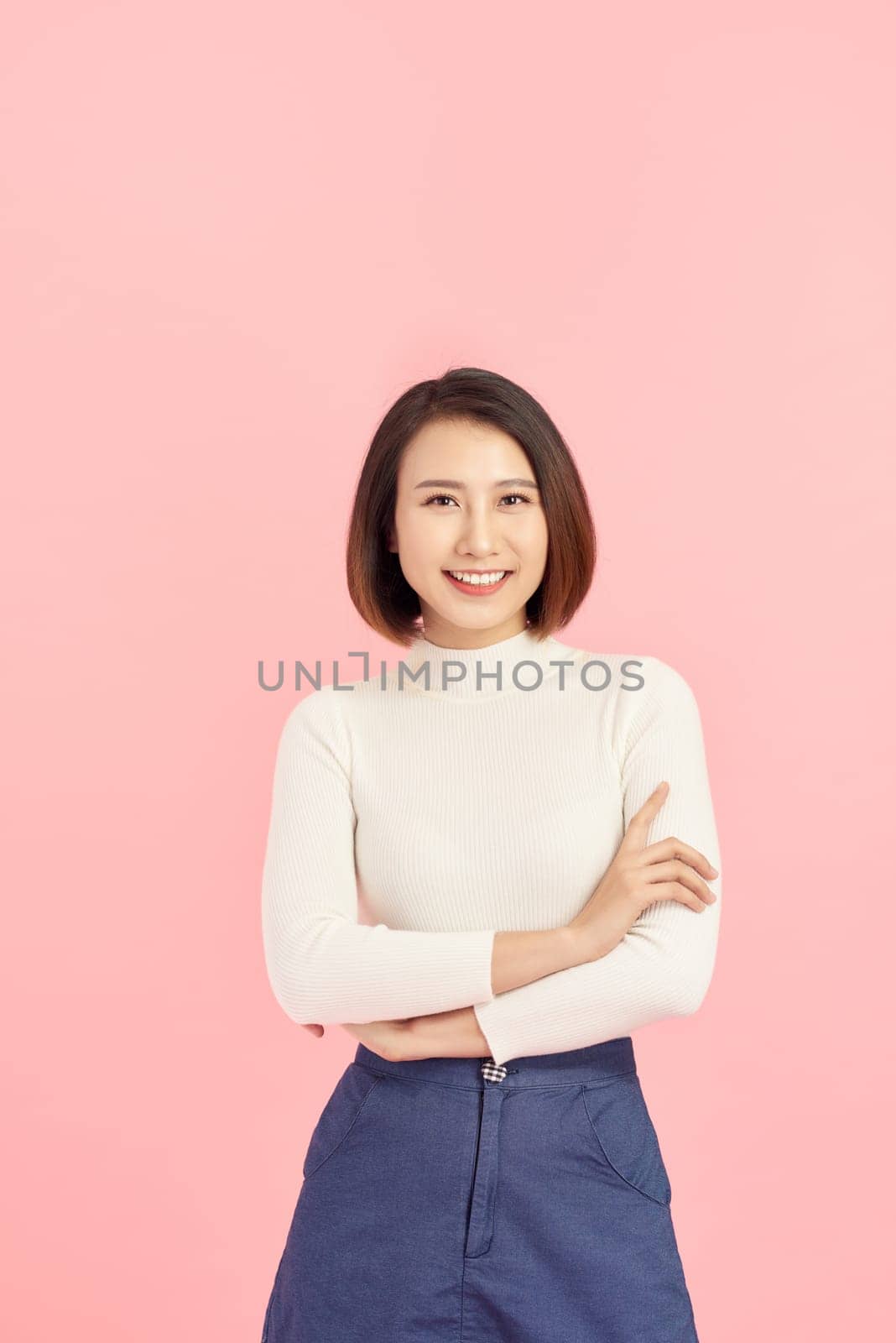 Young Asian woman wearing  sweater standing over isolated pink background happy face smiling with crossed arms looking at the camera. Positive person.
