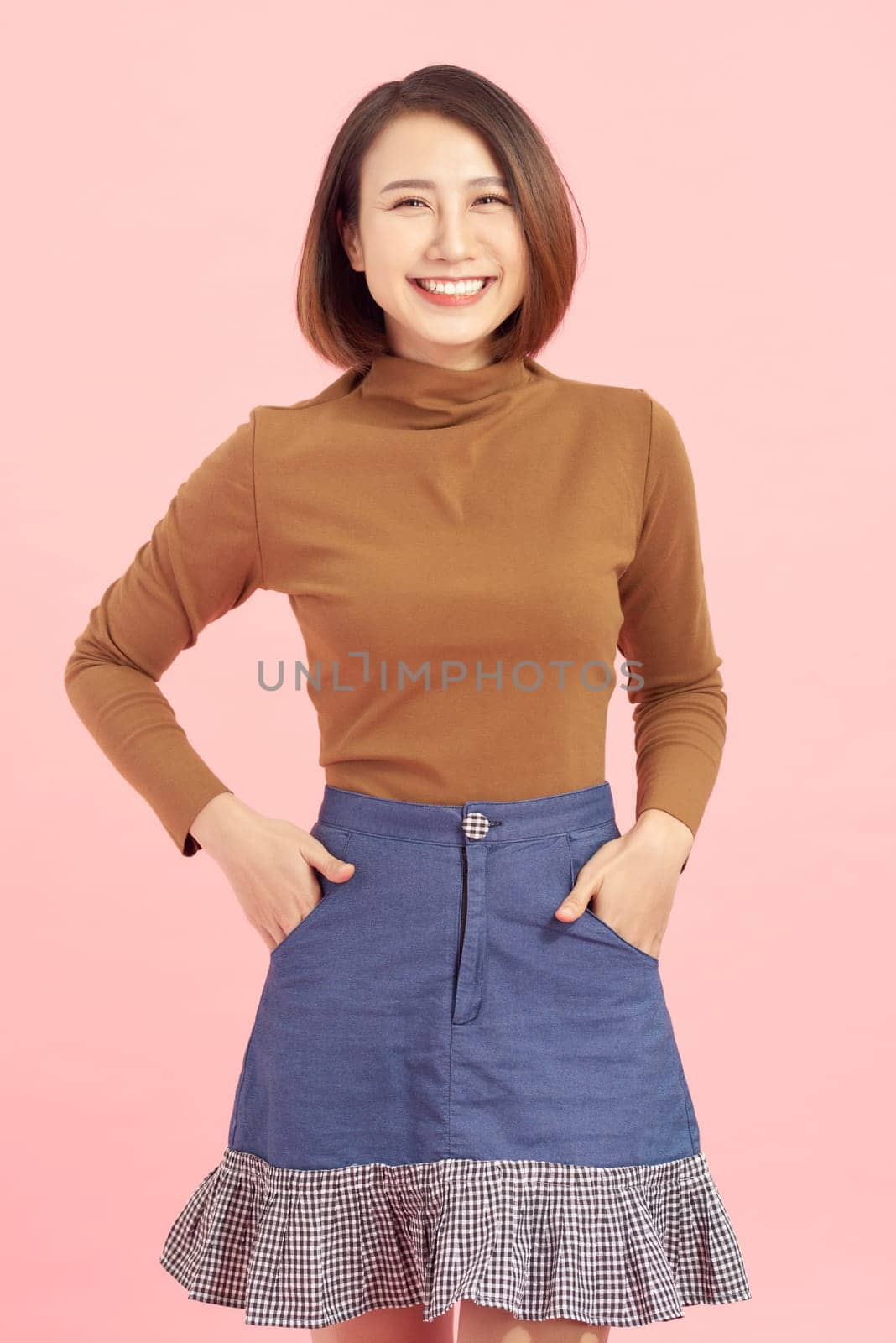 Cheerful young Asian businesswoman standing isolated on pink background.