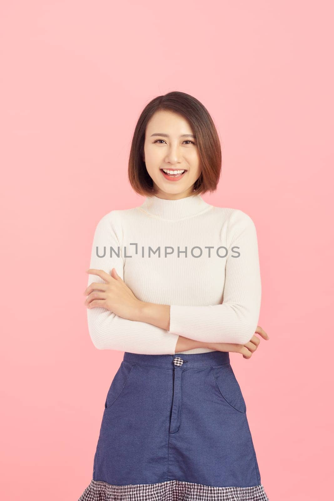 Smiling of Asian woman crossing her arms and standing isolated on pink background. by makidotvn