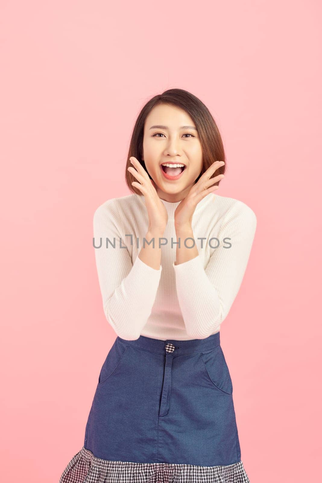 Portrait of an excited asian businesswoman looking at camera isolated over pink background