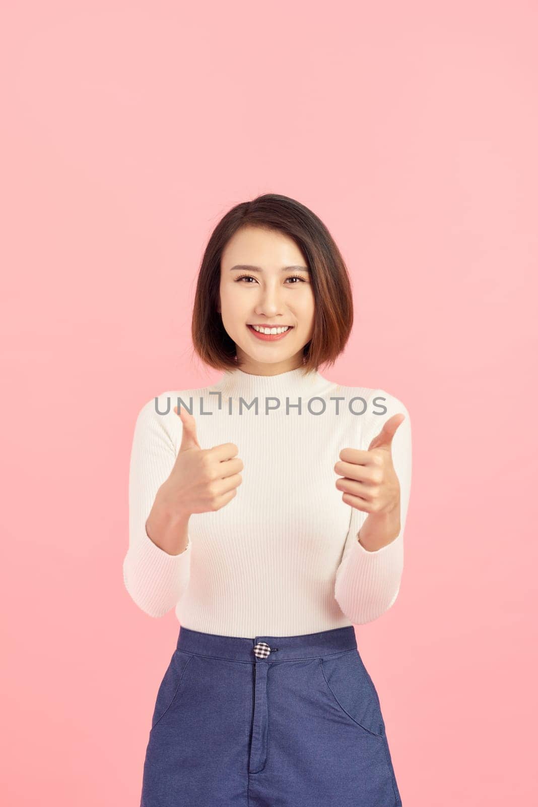 Young Asian woman show thumbs up on pink background by makidotvn