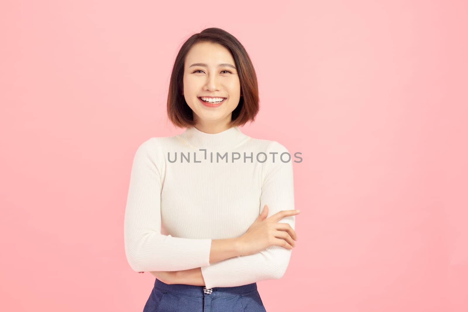 Young Asian woman wearing  sweater standing over isolated pink background happy face smiling with crossed arms looking at the camera. Positive person.