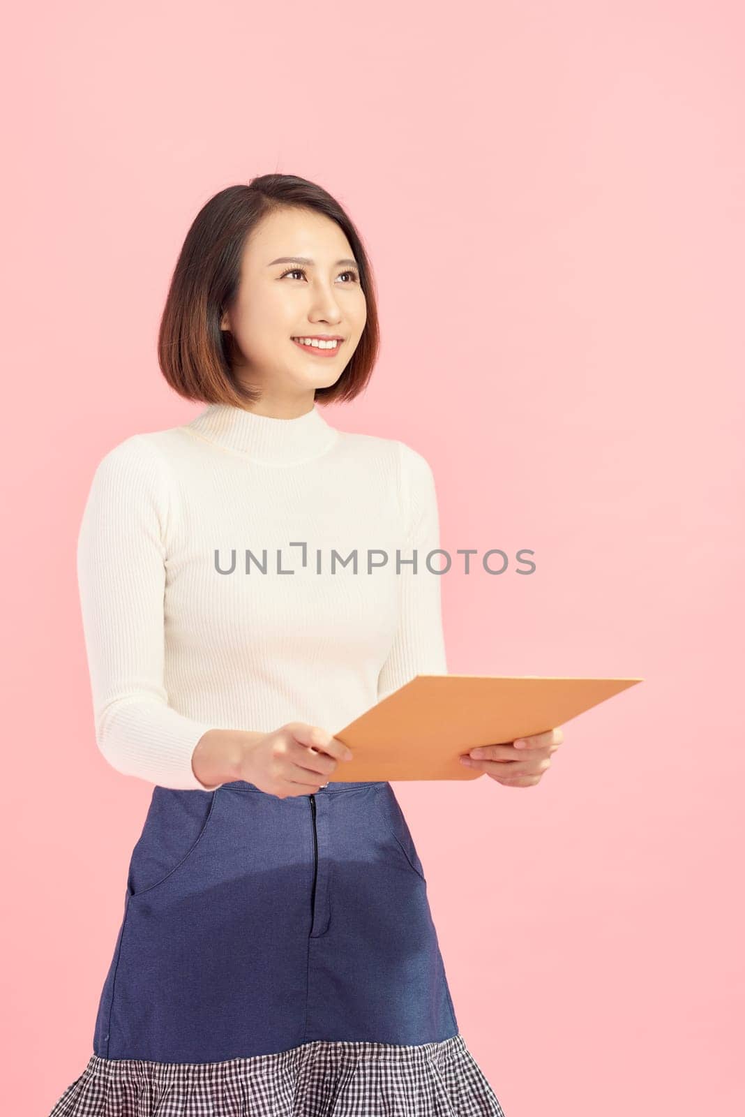 Young Asian business woman holding a file, isolated on pink background