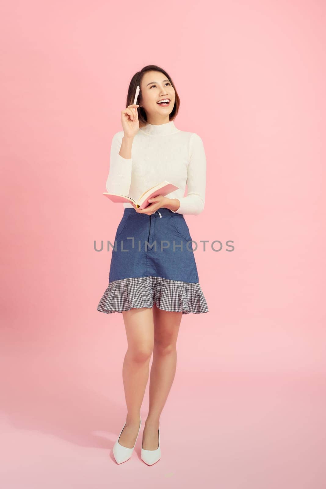 Full length portrait of a smiling beautiful woman holding isolated on a pink background.  by makidotvn