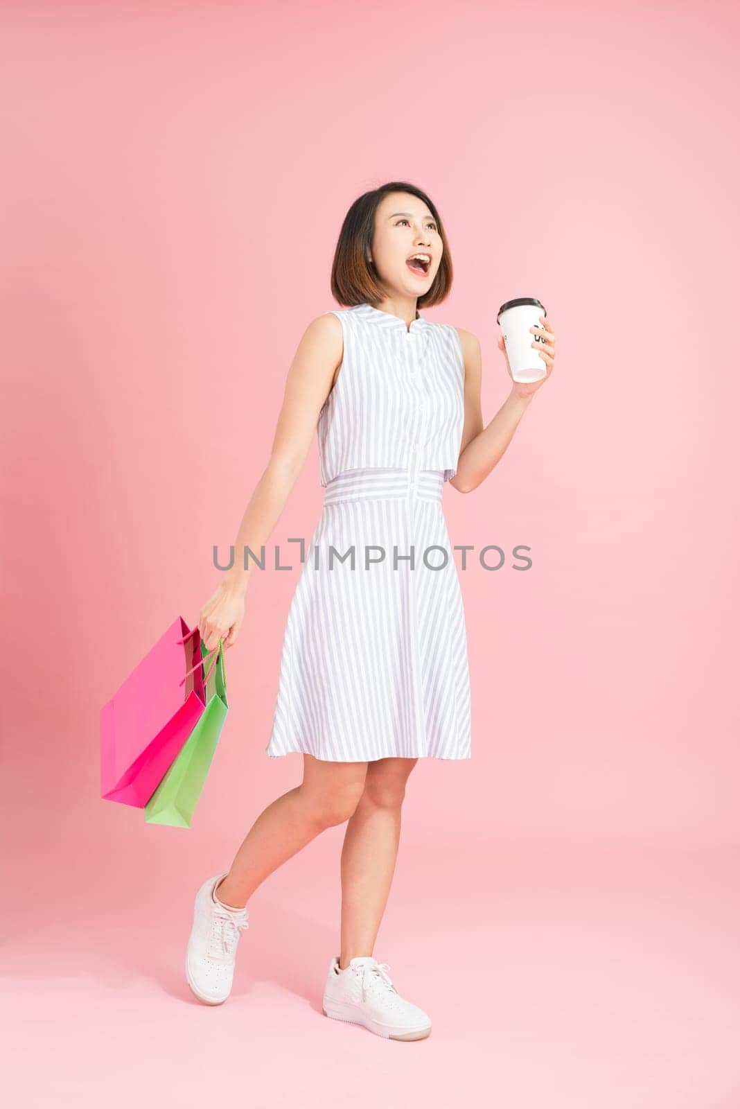 Portrait of woman holding paper bags and coffee after shopping 