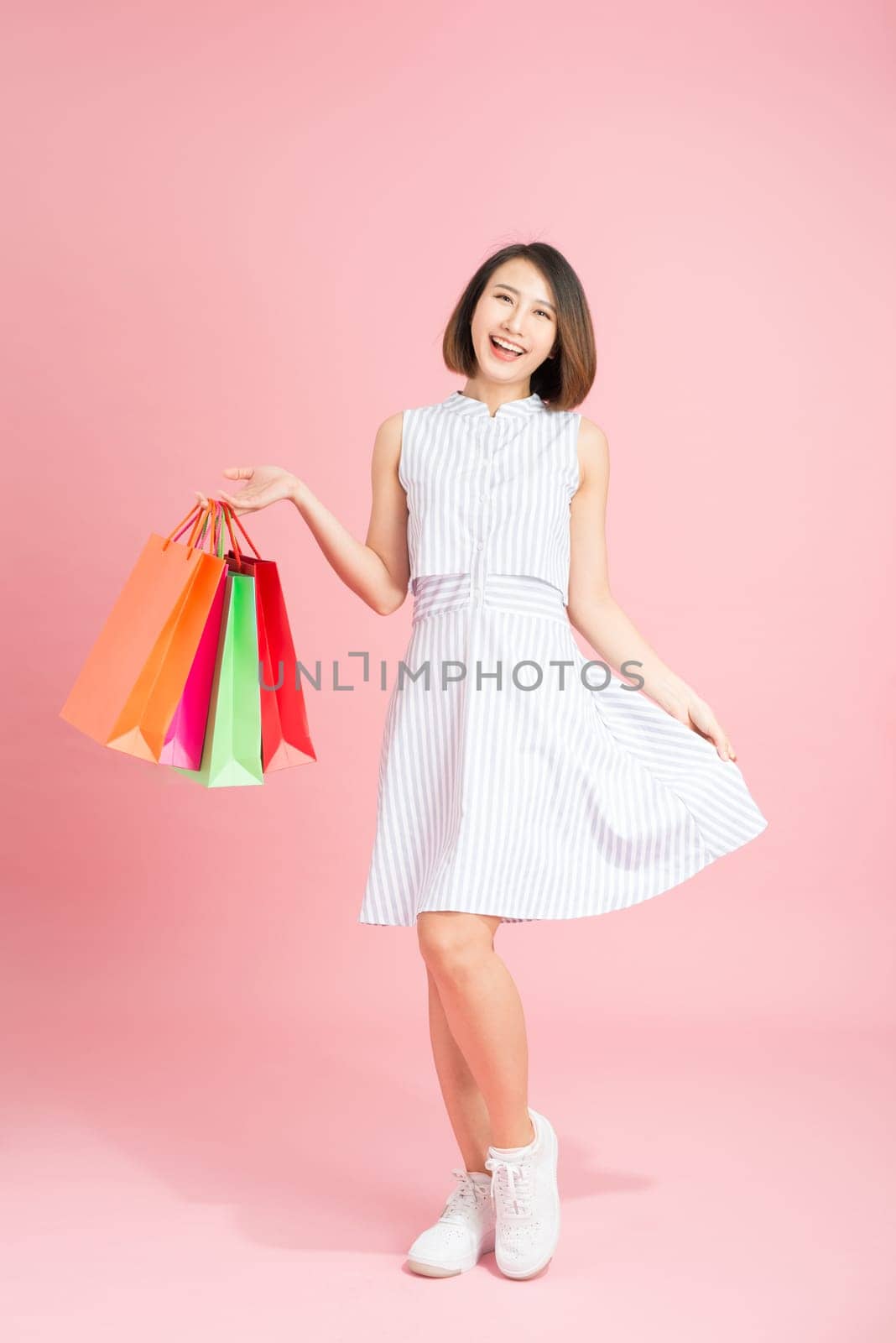 glamor woman in a sundress with packages on a pink background shopping by makidotvn