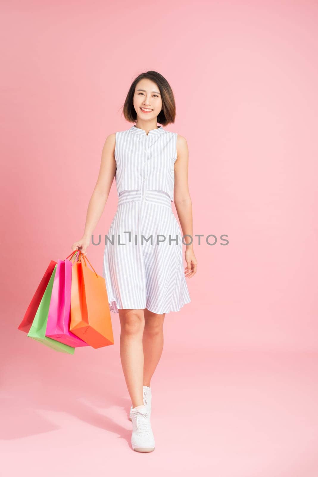 fashionable woman with packages on a pink background by makidotvn