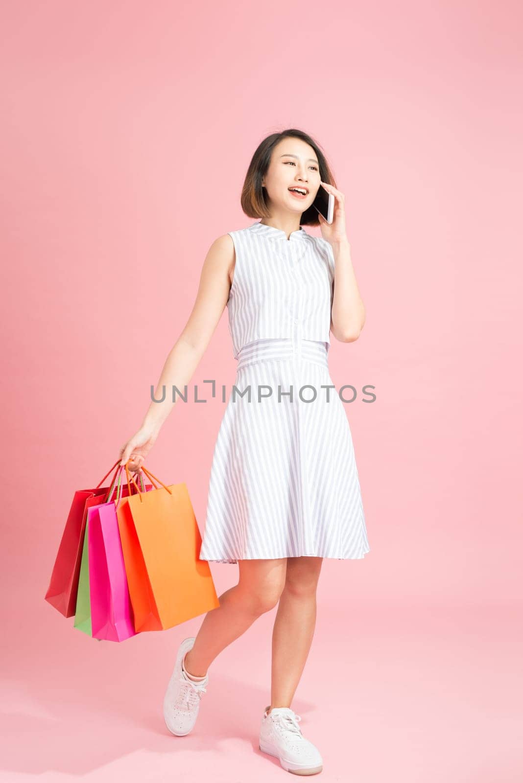 Young asian woman with shopping bags using mobile phone by makidotvn