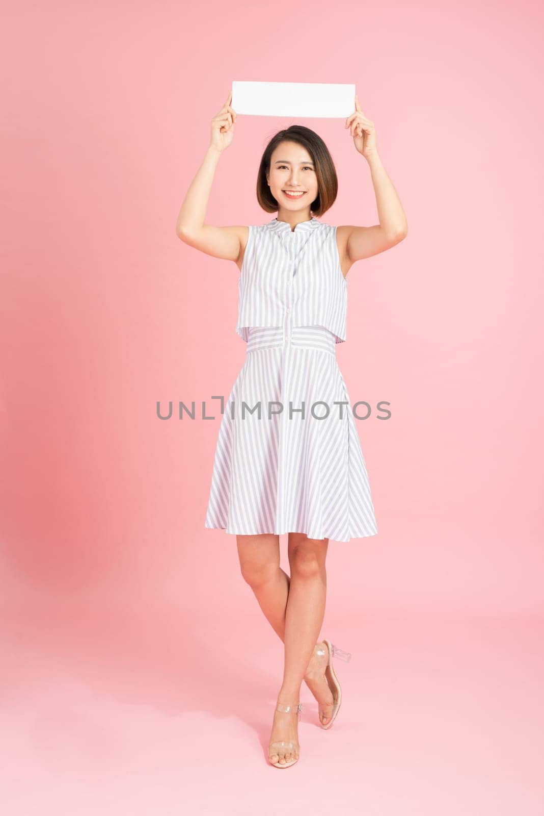 Your text here. Pretty young excited woman holding empty blank board. Studio portrait on white background. Mock up for design by makidotvn