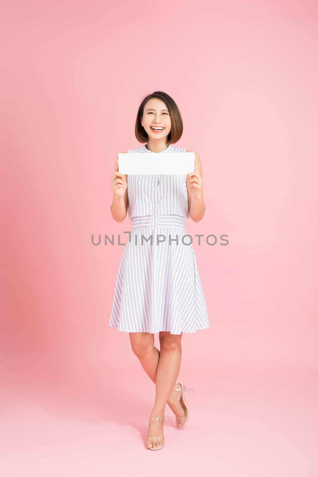 Attractive woman holding paper blank in her hands. Portrait of emotional young woman showing surprised and happy emotions