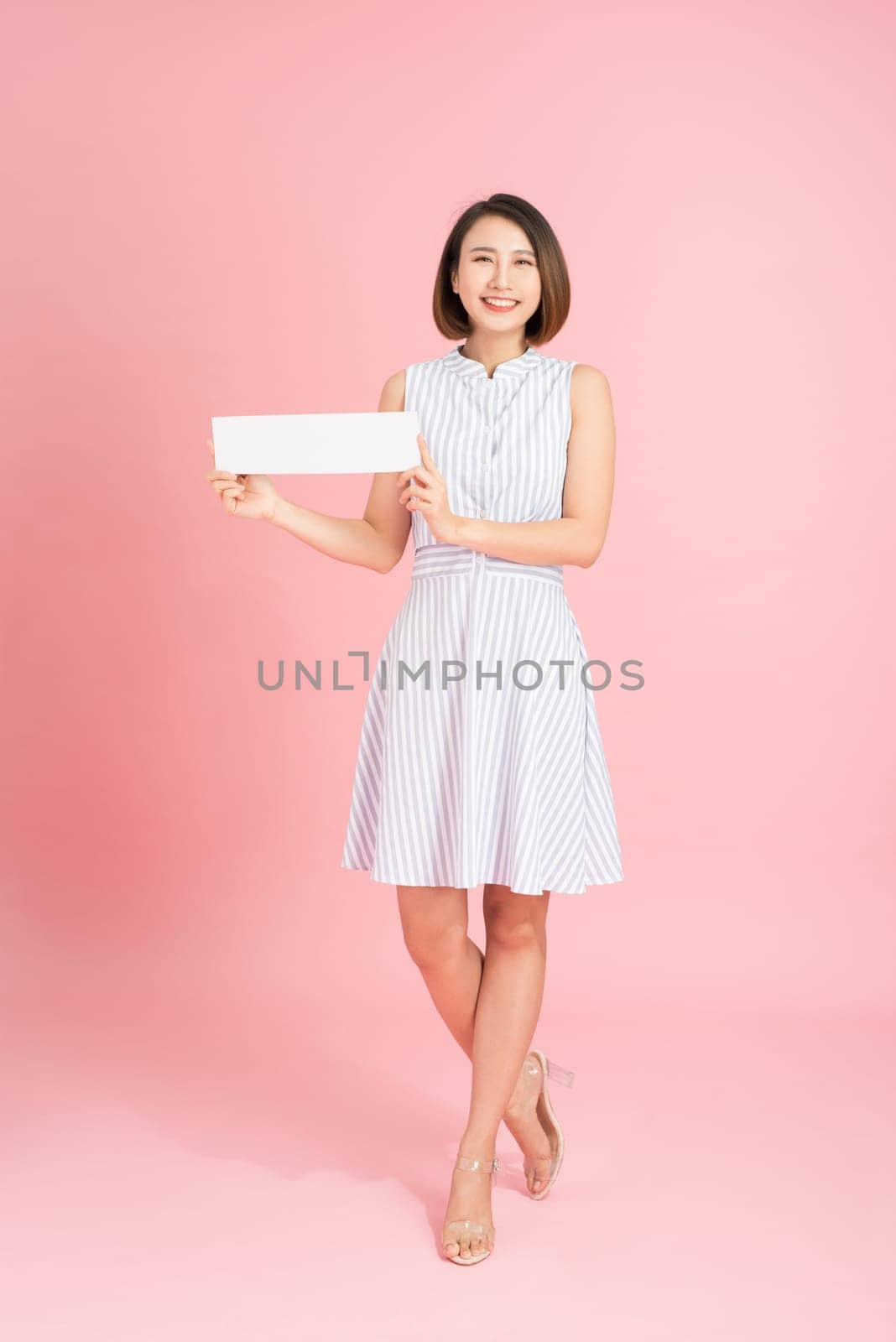 Your text here. Pretty young excited woman holding empty blank board. Studio portrait on white background. Mock up for design