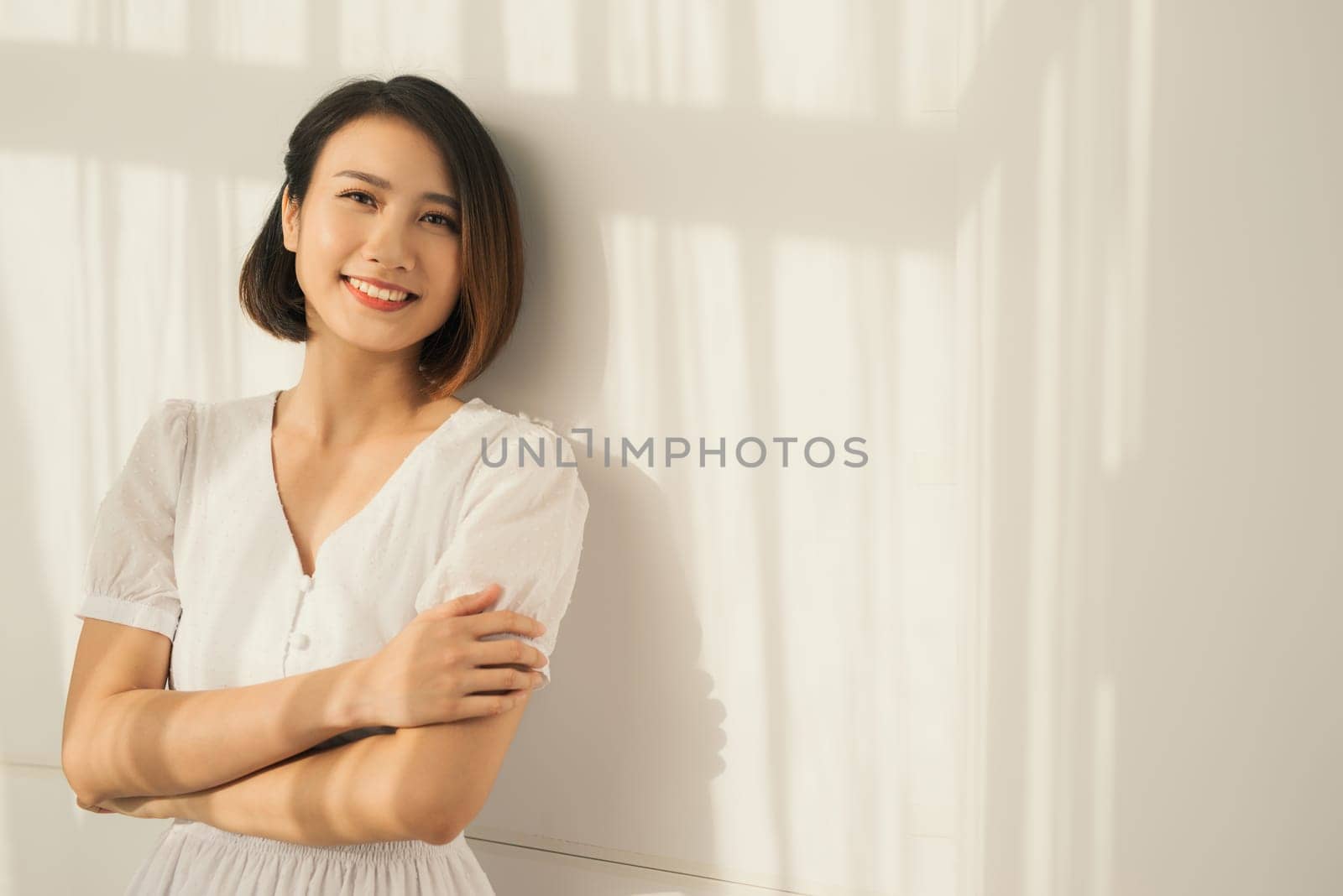 Beautiful elegant woman standing against the wall, the sunlight is beautifully falling by makidotvn