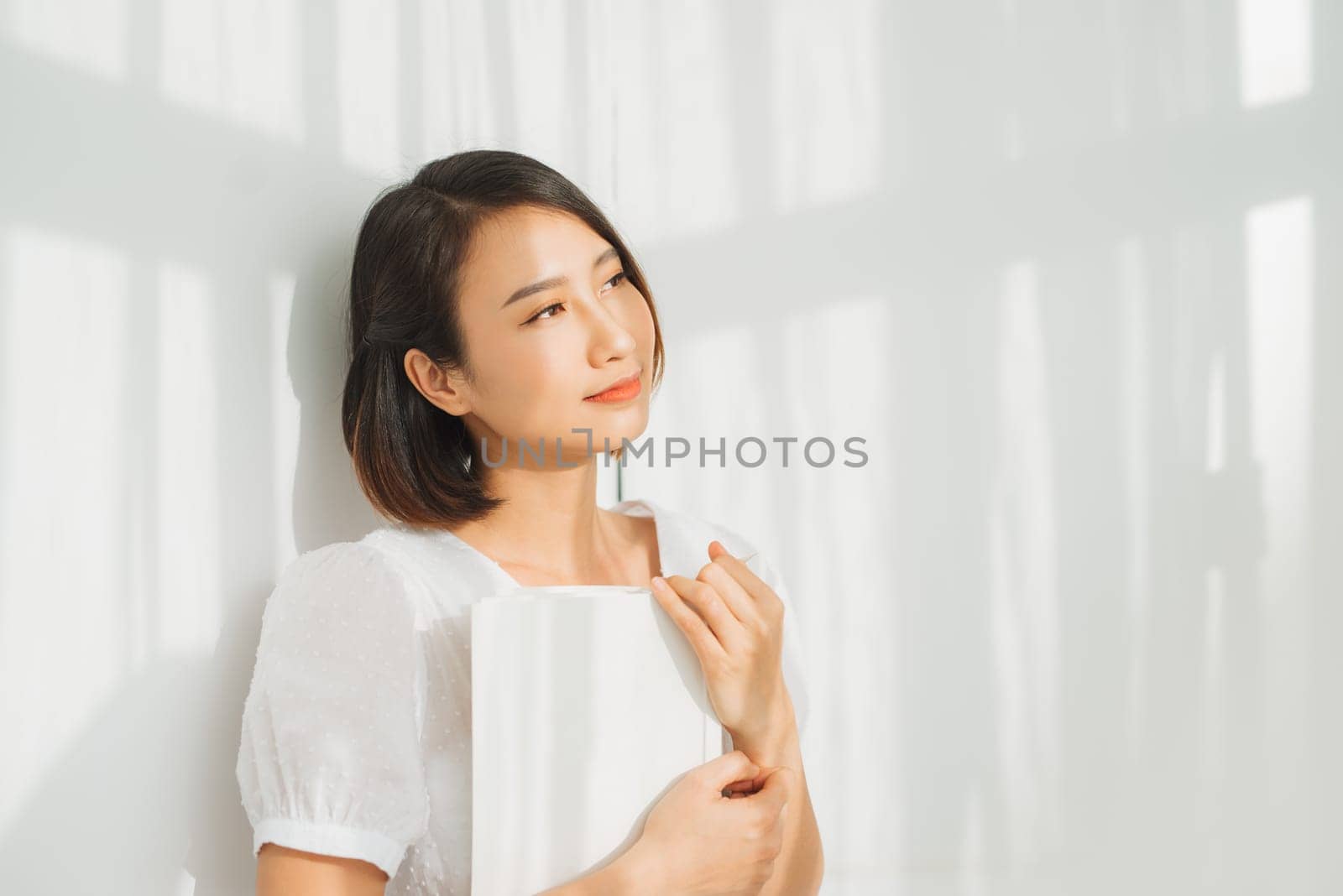 Young woman reading a book while relaxing at home with sunlight.