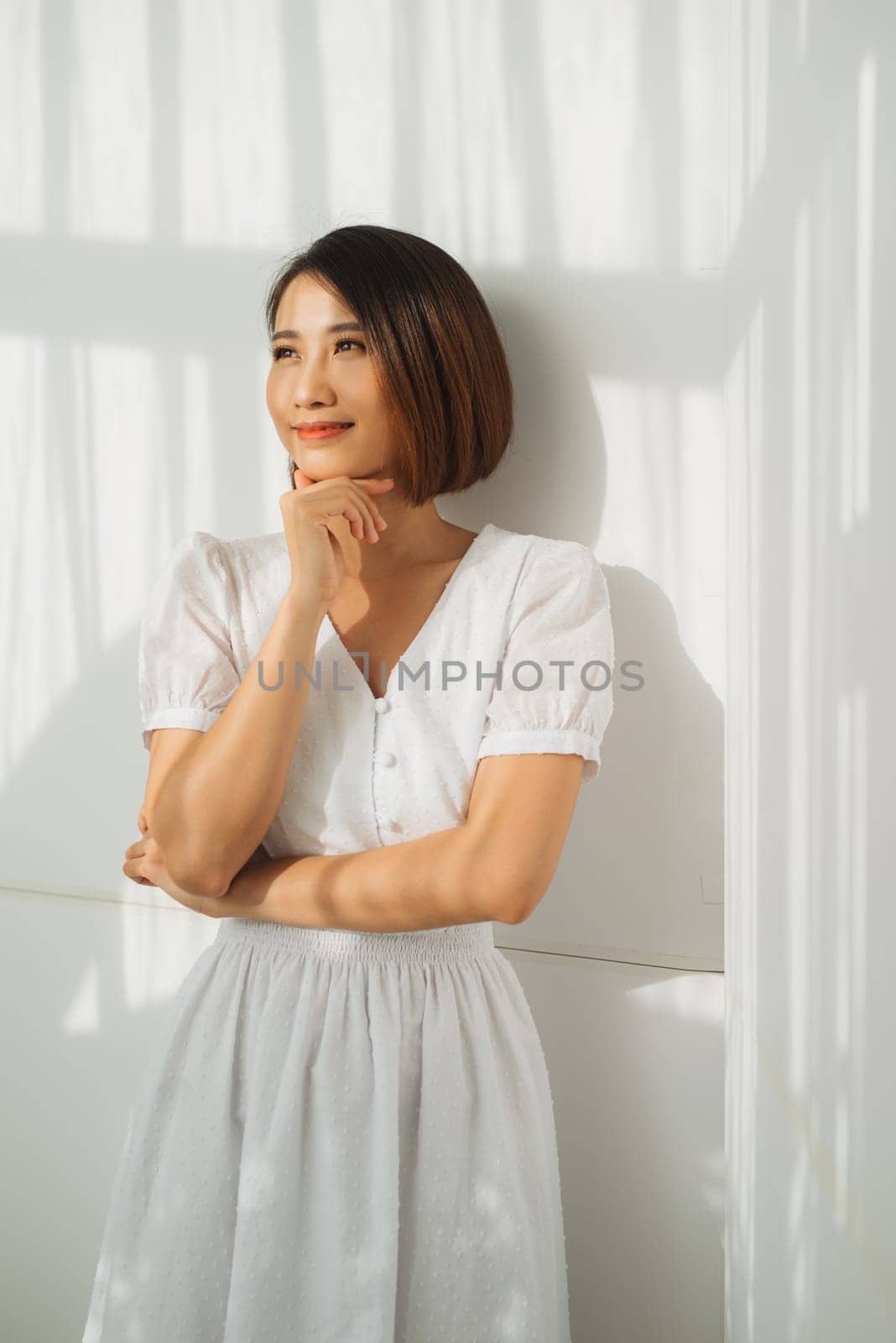Beautiful elegant woman standing against the wall, the sunlight is beautifully falling by makidotvn