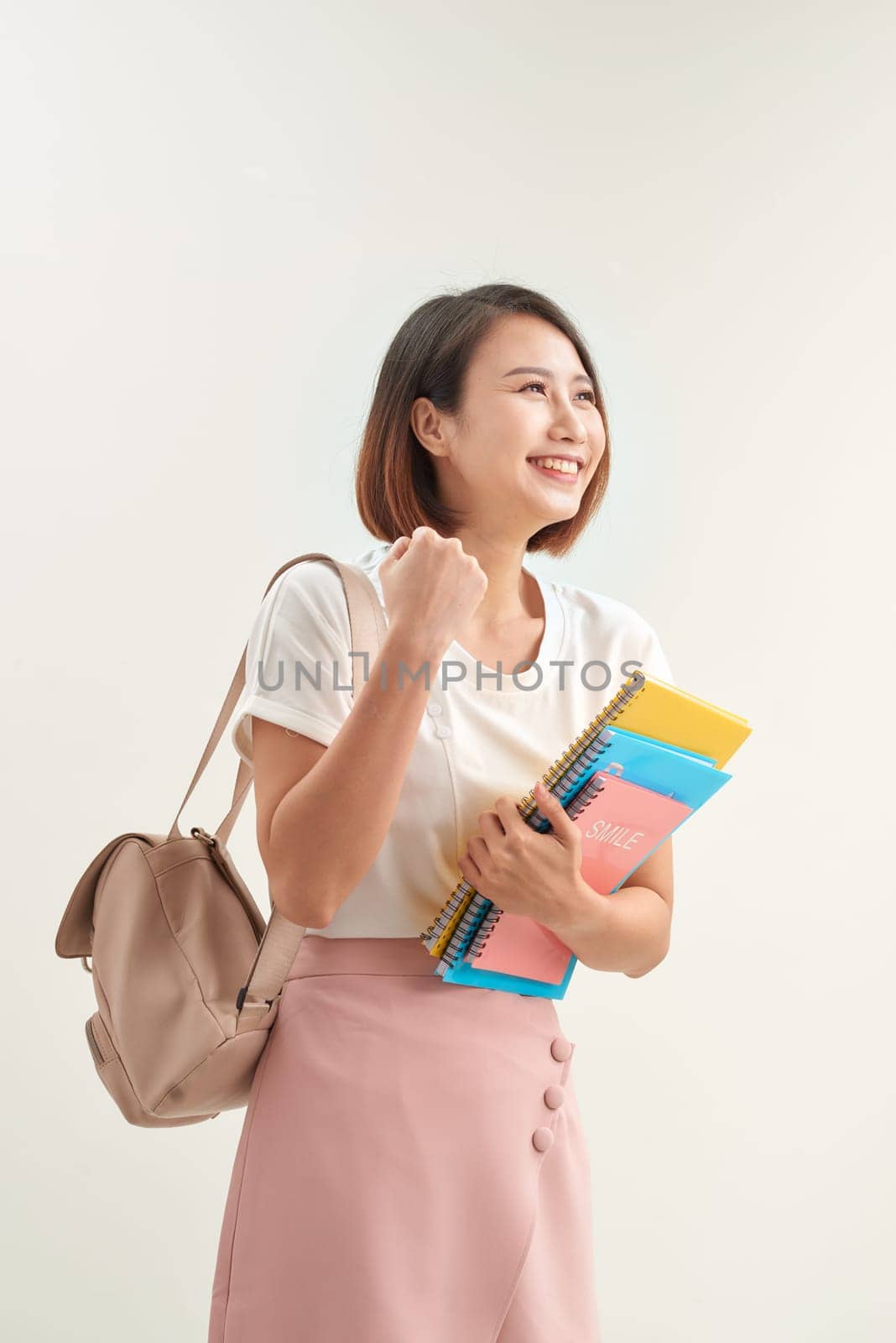 Young happy attractive asian student smiling to camera expression winner by raising hand and arm up to celebrate success on white