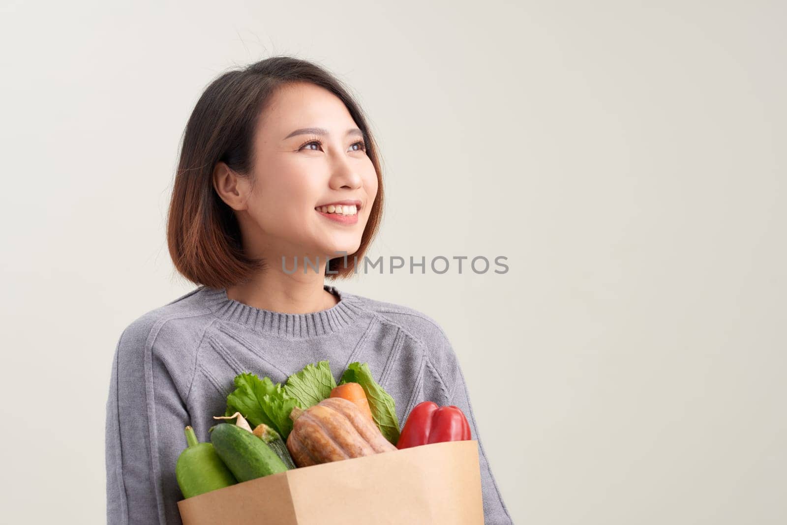 Cheerful woman holding a shopping bag full of groceries by makidotvn