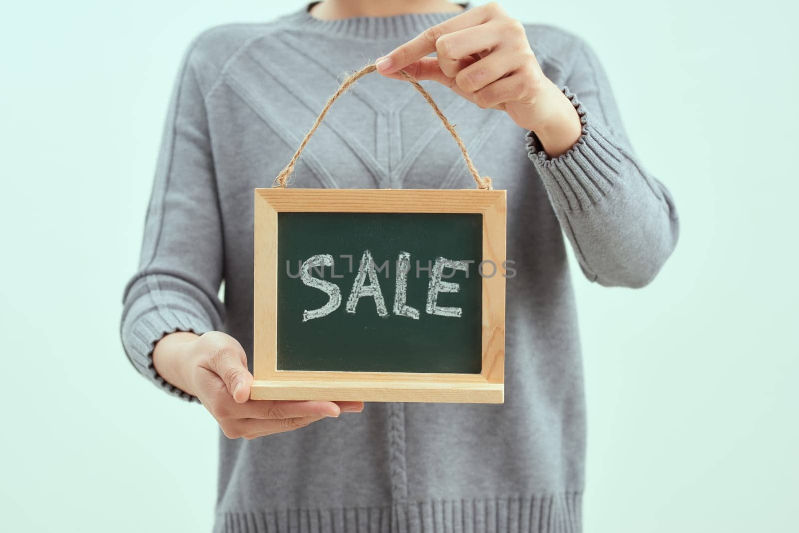 Smiling woman holding sale sign isolated over blue