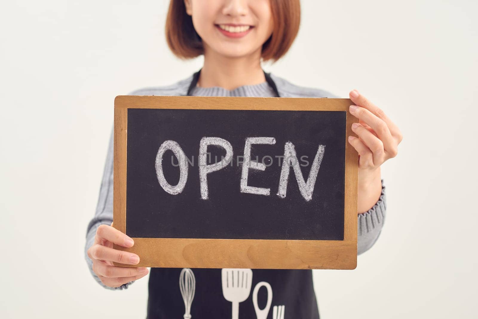 It's open here. A smiling woman is holding a sign with the inscription "open" on a white background isolated.