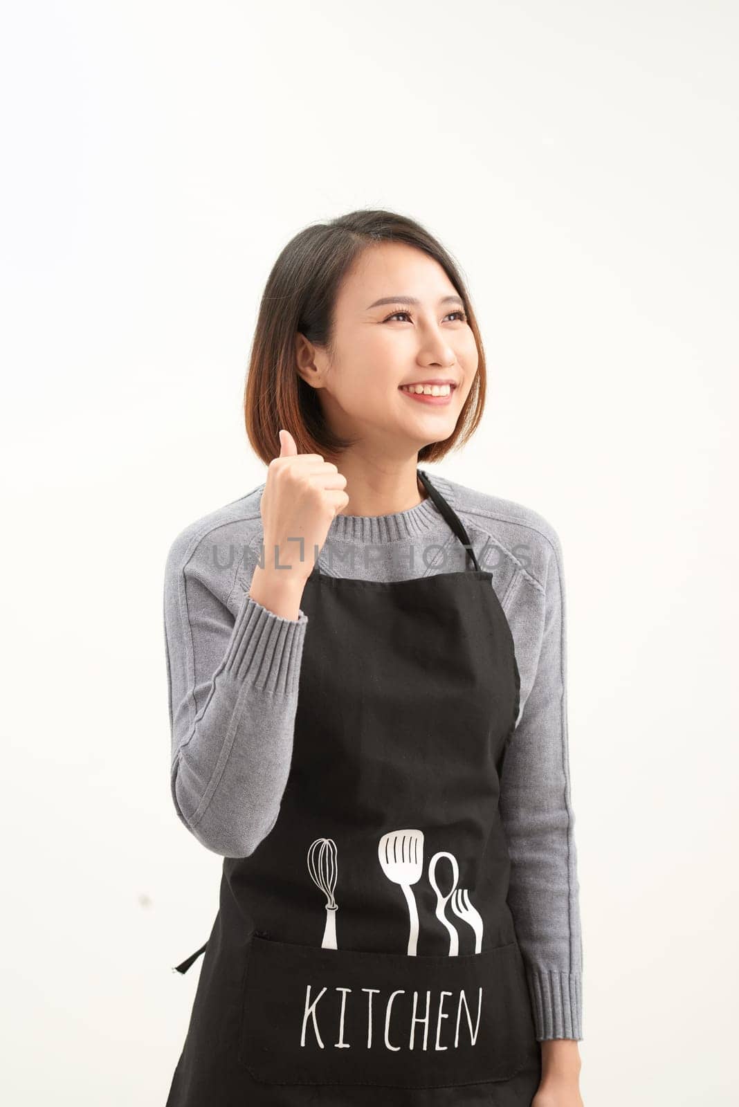Young asian shopkeeper woman wearing apron over isolated white background doing happy thumbs up gesture with hand. by makidotvn