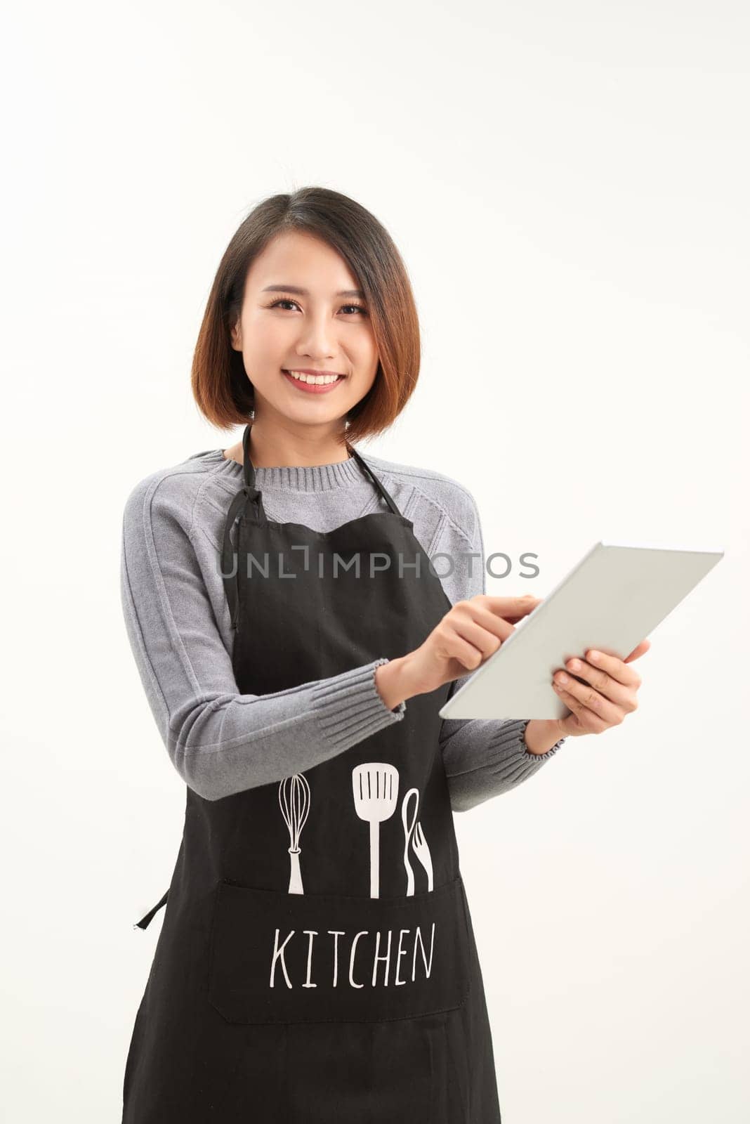 Successful hypermarket employee with black apron holding modern tablet isolated on white background with copyspace