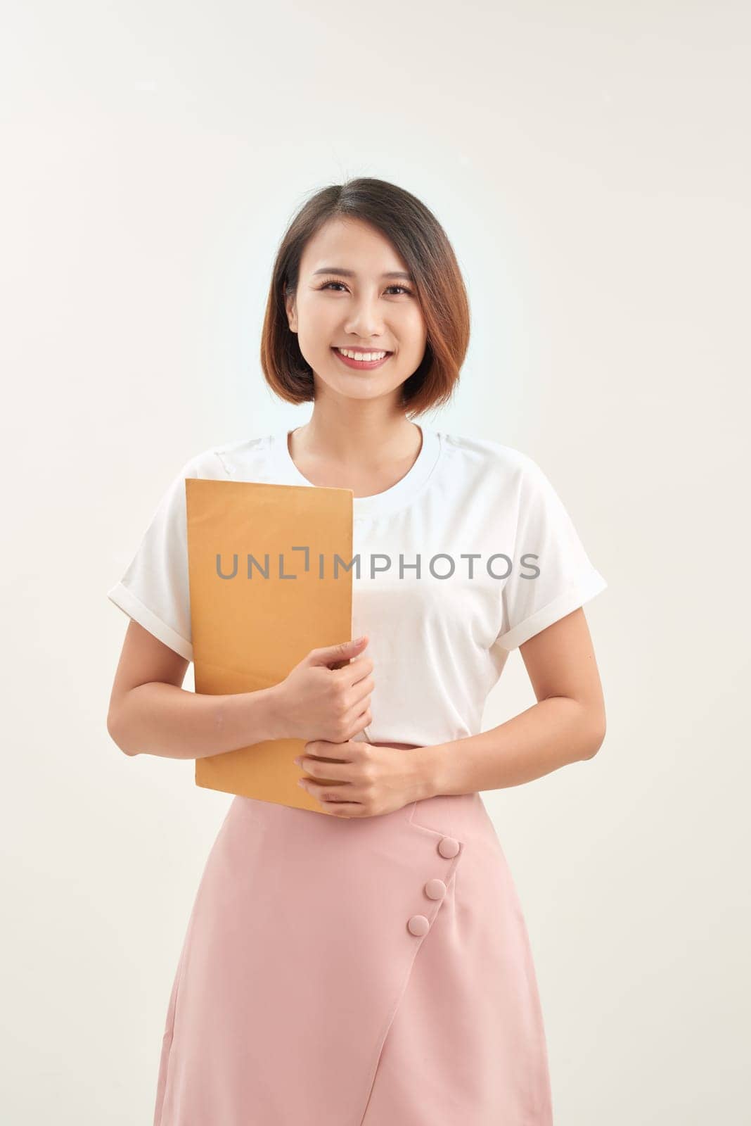 Young asian woman holding a self sealing brown envelope document on white background by makidotvn