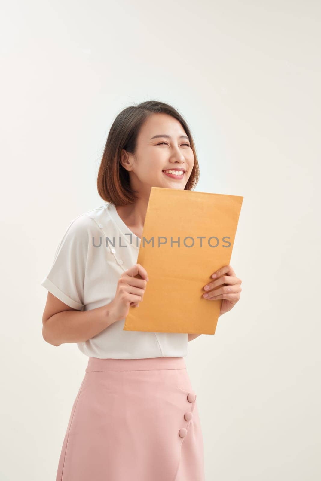 Young asian woman holding a self sealing brown envelope document on white background by makidotvn